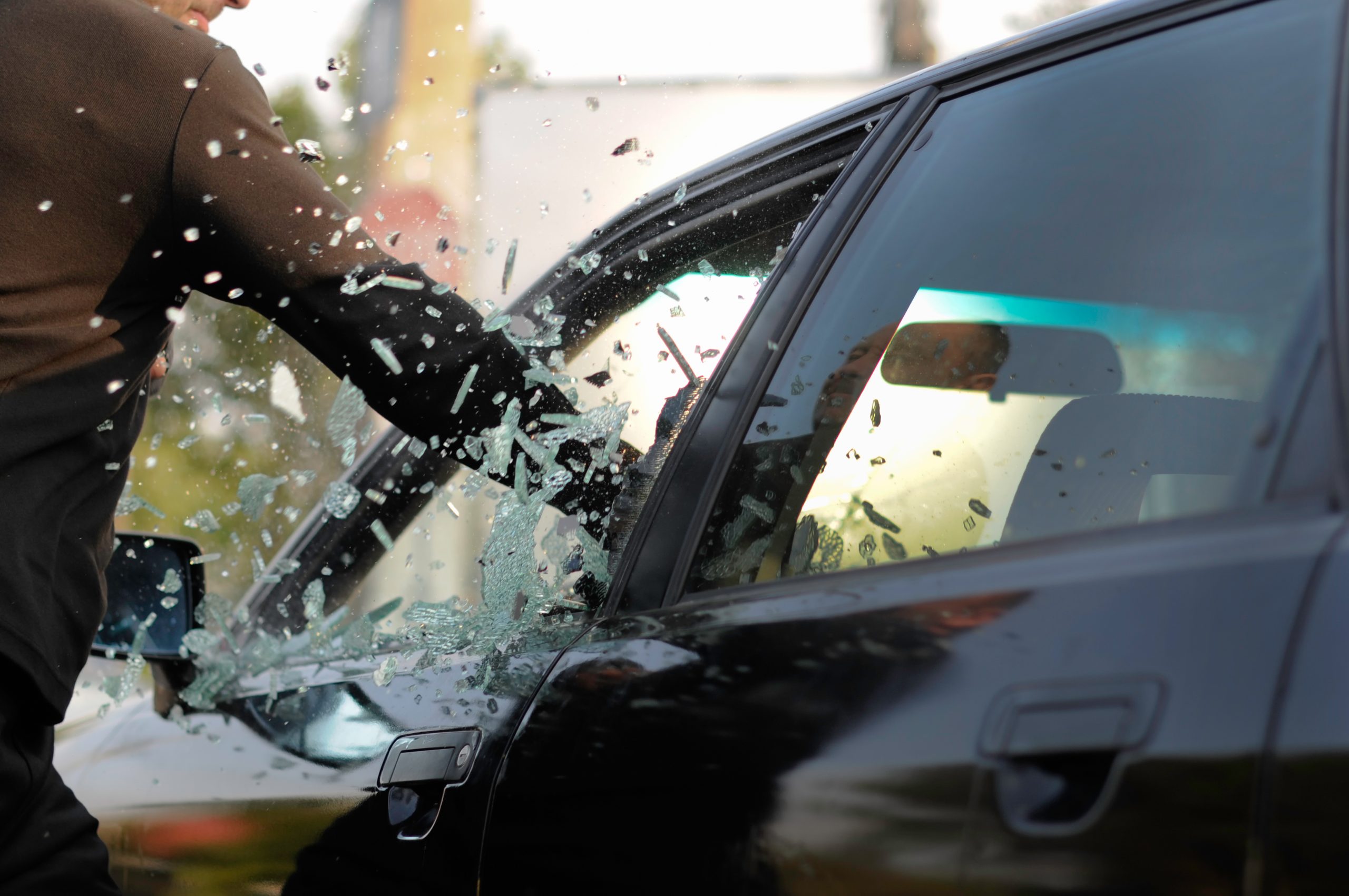 Dief slaat raam in van auto.