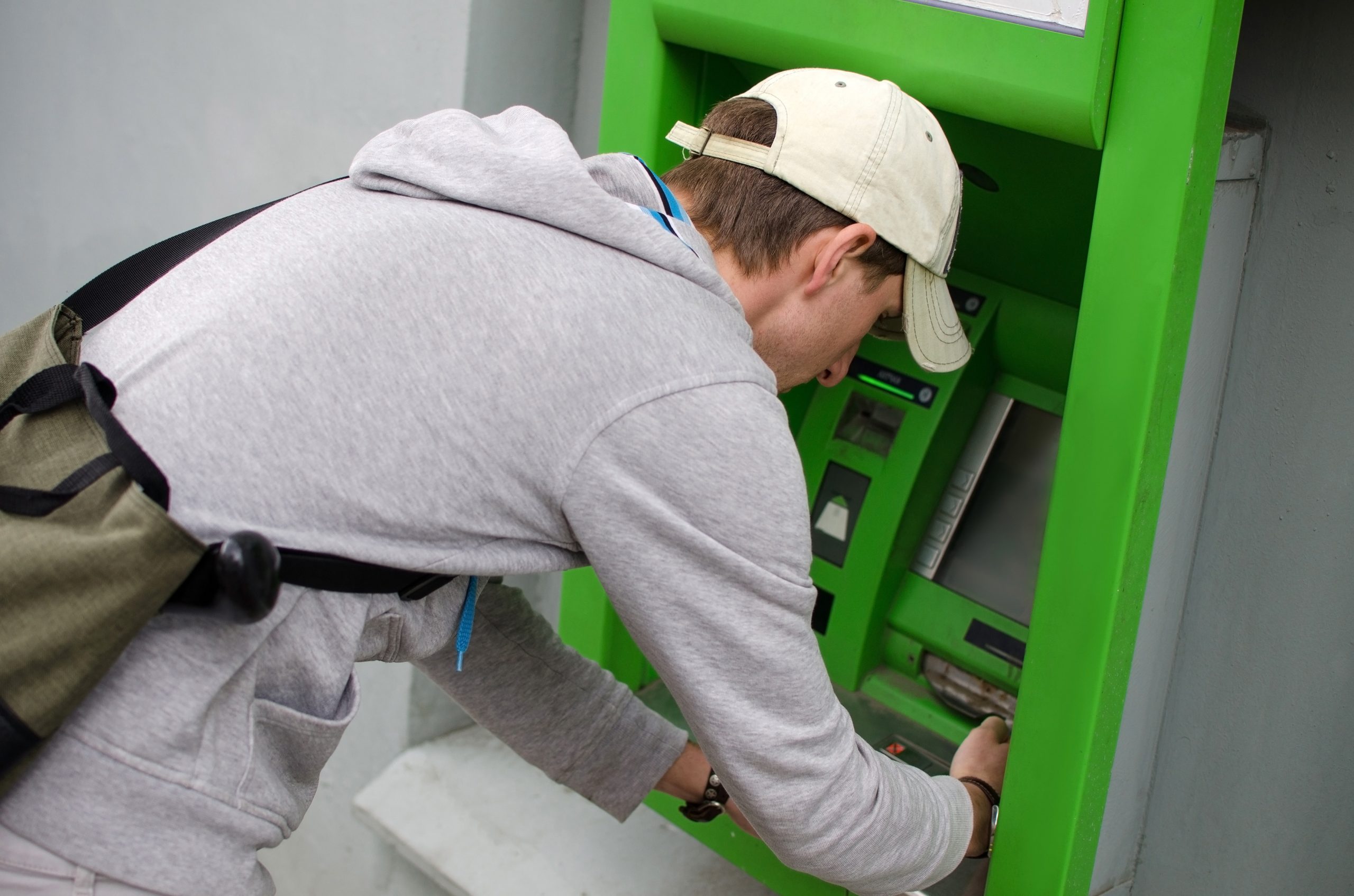 Een jongen neemt geld op bij en pinautomaat. Ter illustratie van het begrip Geldezel in het CCV-dossier Cybercrime.
