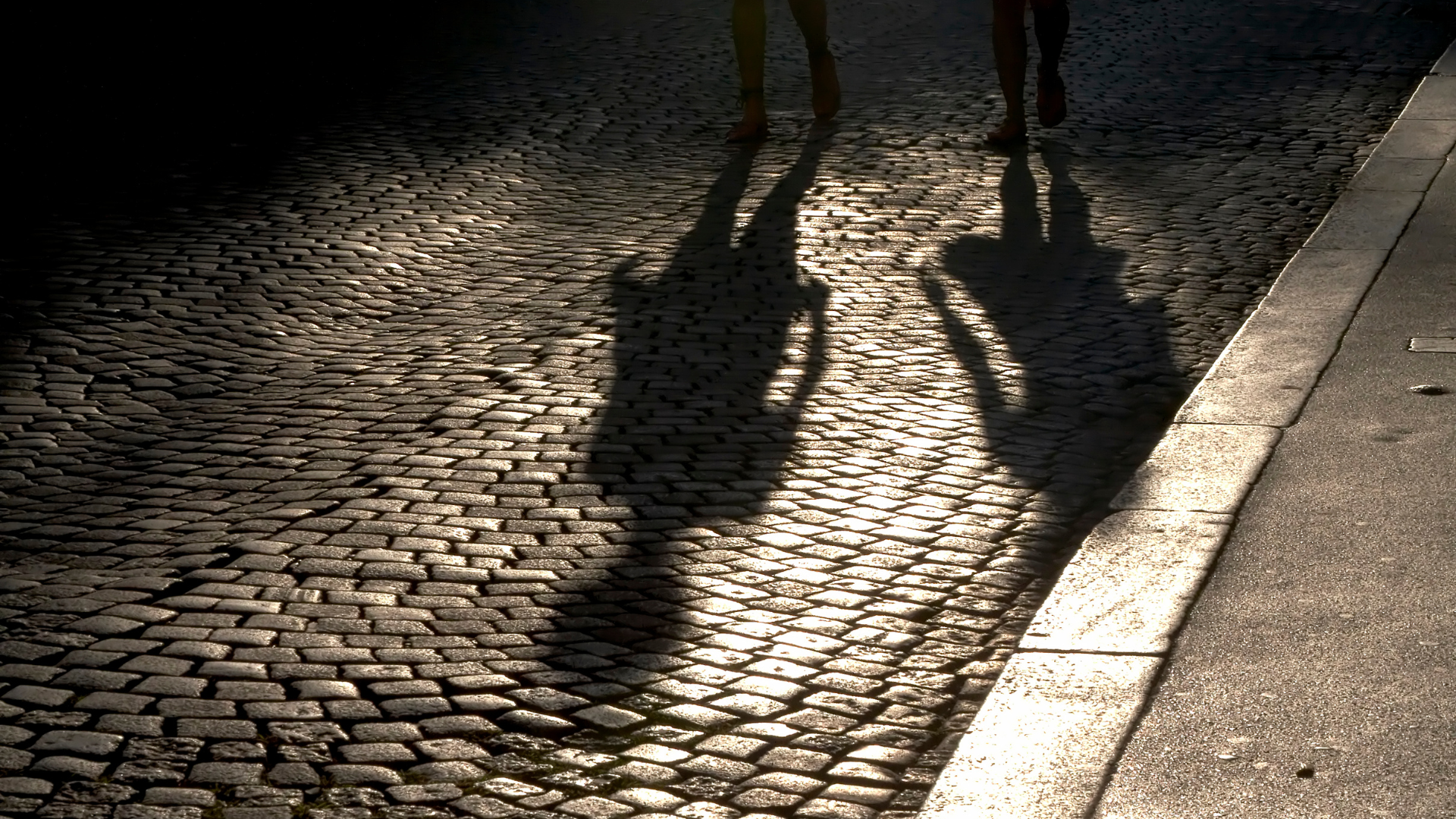 Twee schaduwen van personen die in het donker op straat lopen. Ter illustratie van het CCV onderwerp Veiligheidsbeleving.