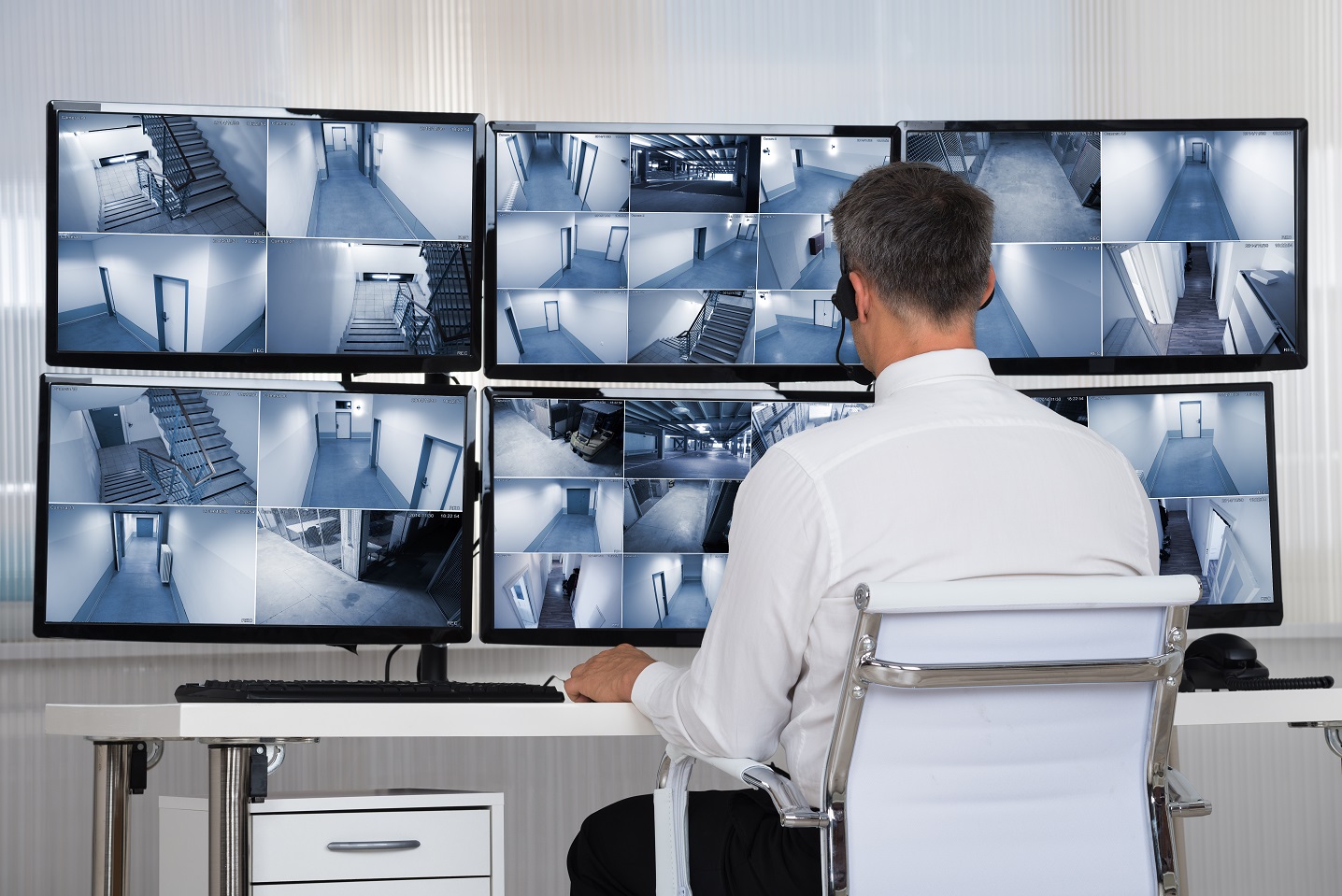 Een medewerker kijkt naar camerabeelden in een alarmcentrale.