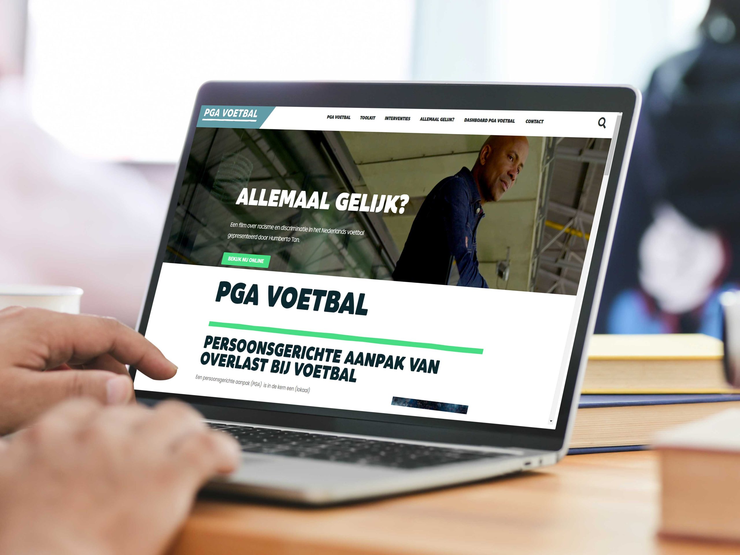 Persoon op laptop. Op het scherm staat de website open van PGA Voetbal.