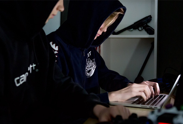 Twee jongeren met zwarte hoodies aan, zitten achter een laptop. Ter illustratie van een artikel uit Secondant.