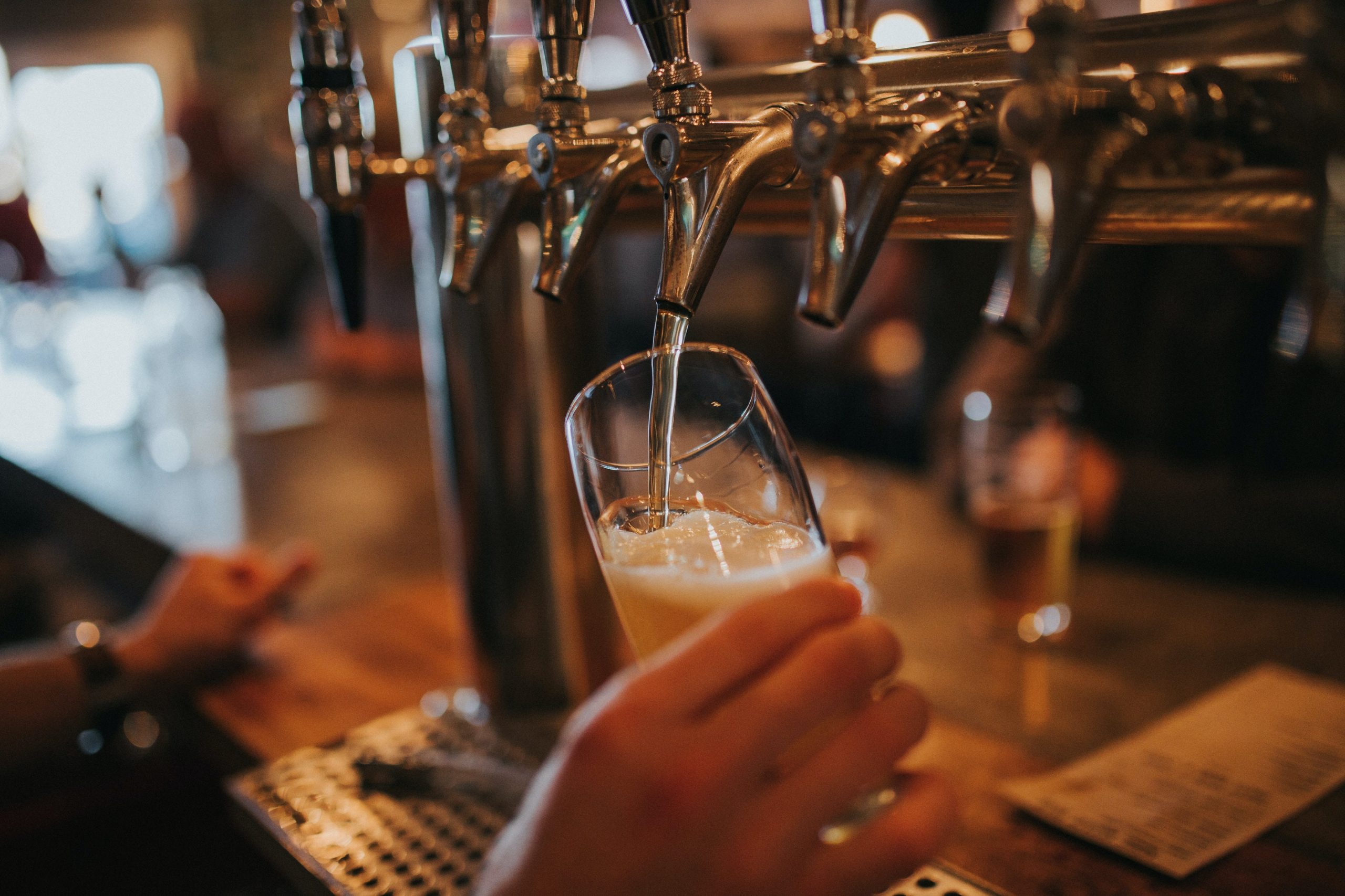 Een persoon achter de bar tapt een biertje. Ter illustratie van het thema Veilig Uitgaan van het CCV.