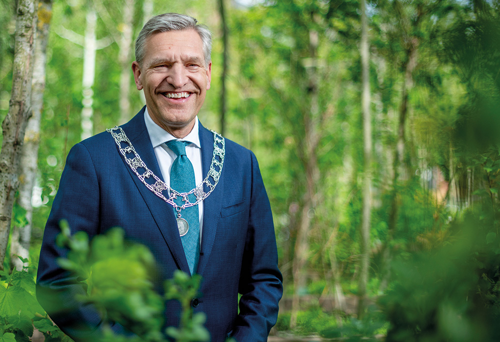 Portretfoto van Sybrand van Haersma Buma, waarbij hij buiten staat in het groen.