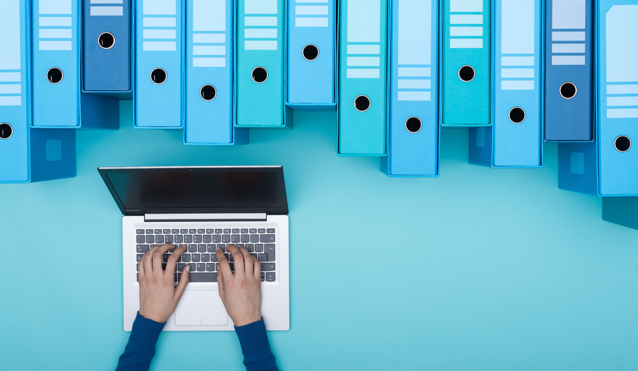 twee handen typen op een laptop. De achtergrond is blauw met bovenin op een rij blauwe documentmappen. Ter illustratie van een bericht over cybercrime en het mkb.