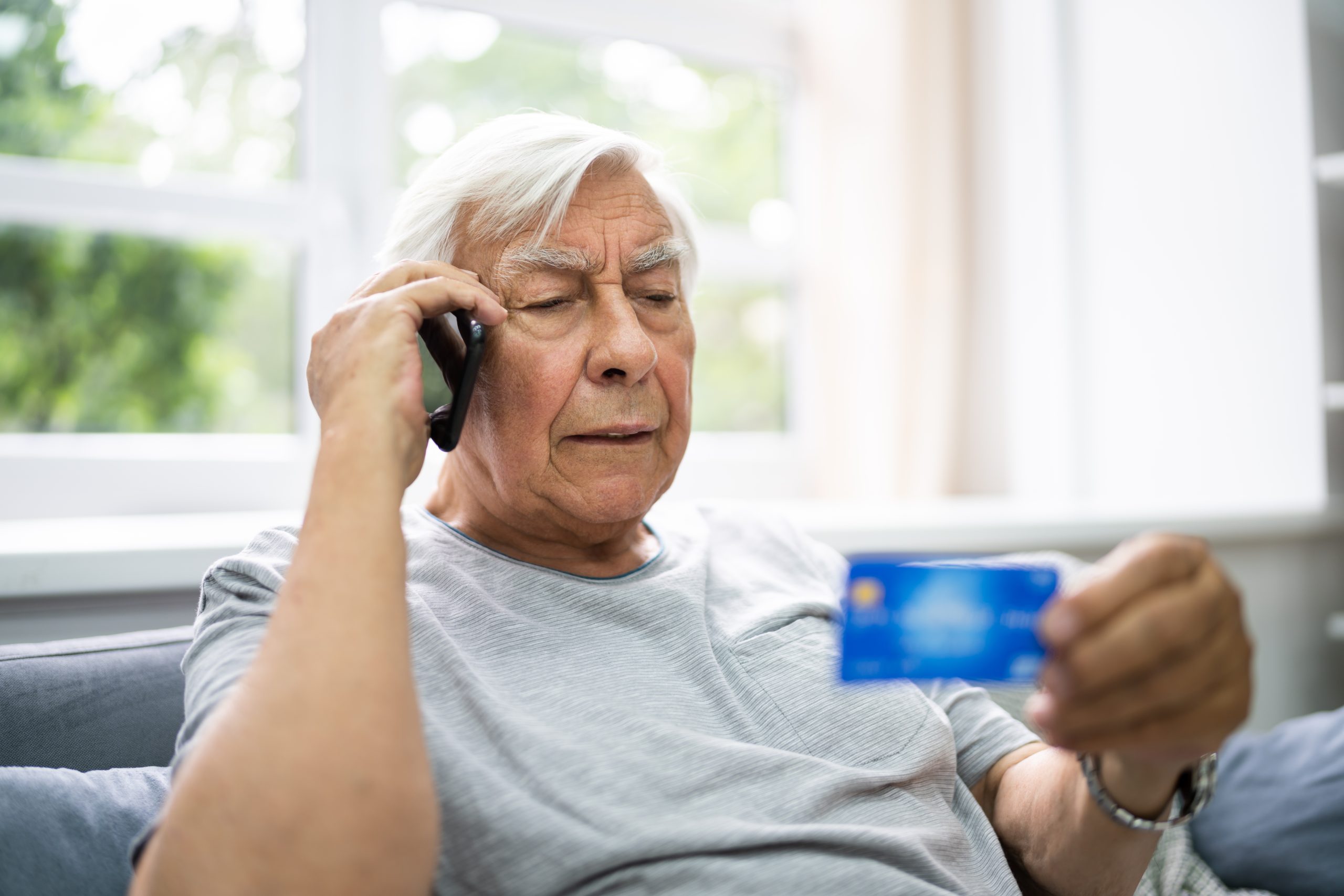 oudere man aan telefoon met bankpas