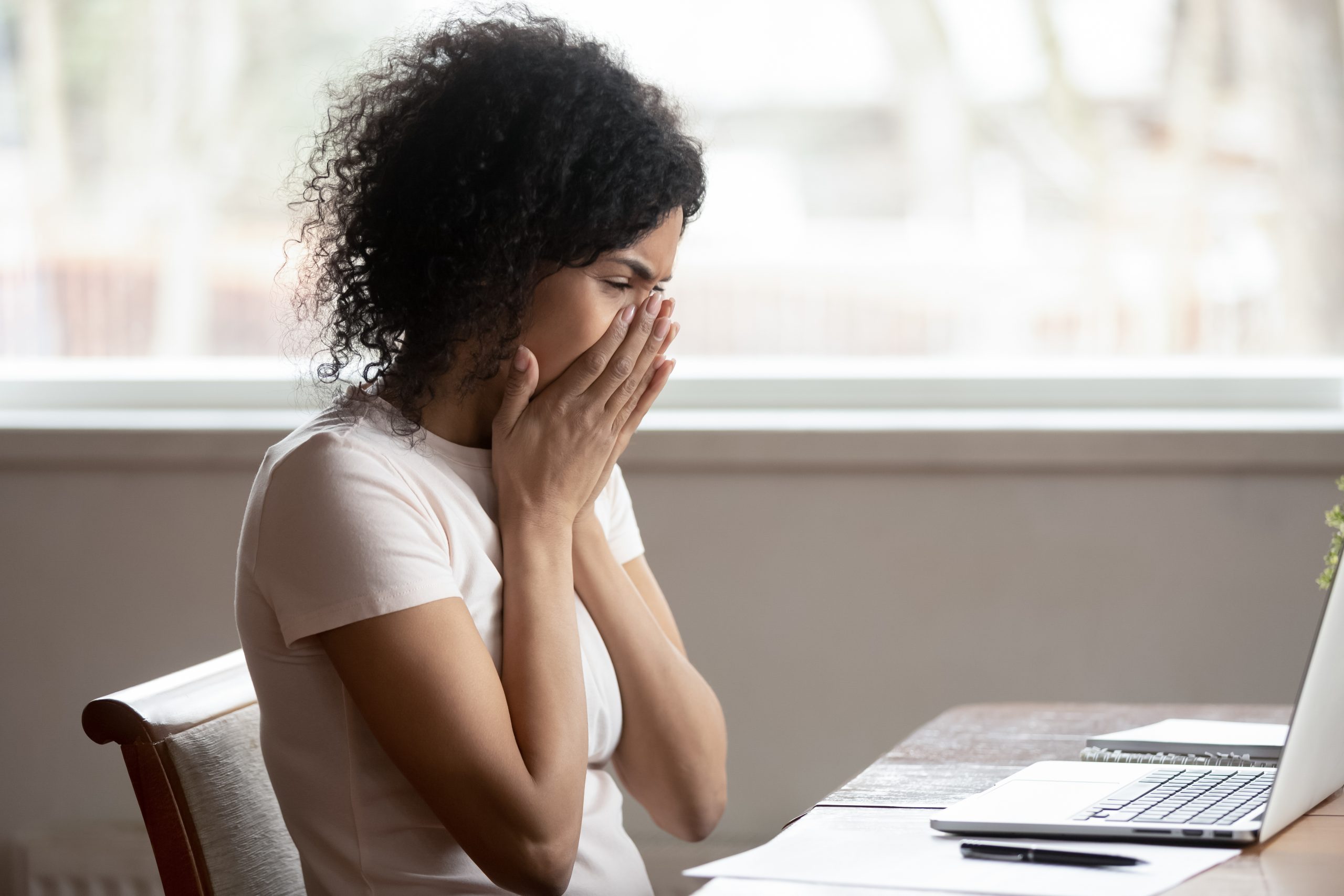 vrouw met handen voor mond voor laptop