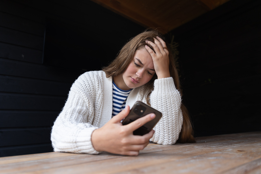Meisje kijkt bezorgt op haar mobiel.